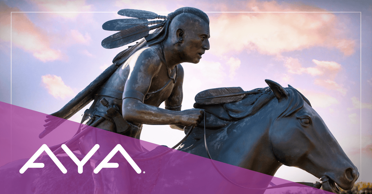 Bronze sculpture of a Chickasaw rider on horseback against sunset sky
